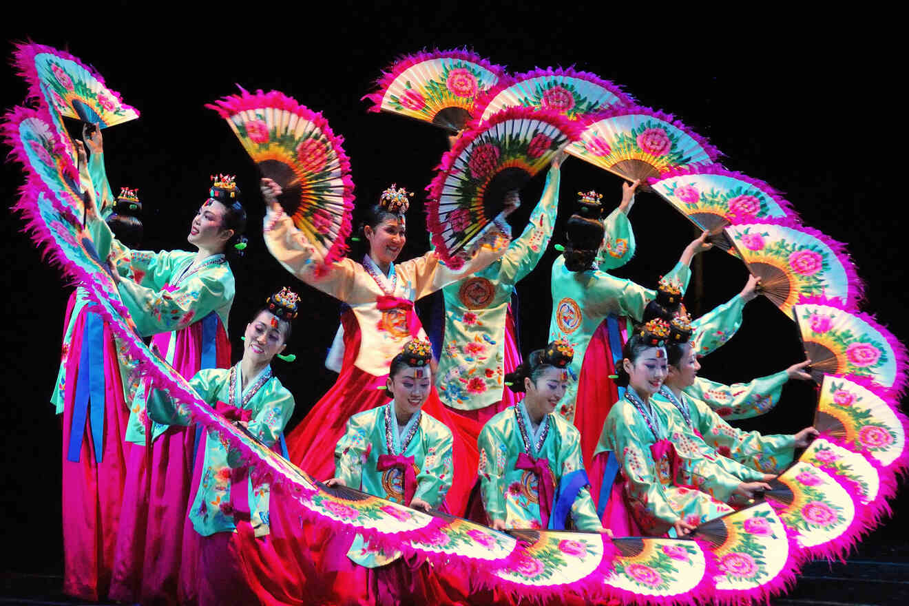 Traditional Korean dancers in vibrant costumes performing with colorful fans.