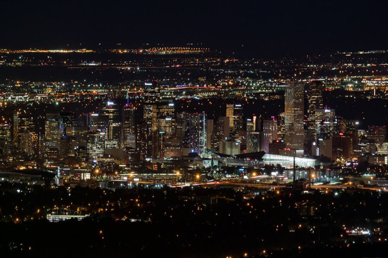 Nighttime panorama of downtown Denver, featuring illuminated buildings and busy streets, showcasing the city's vibrant nightlife