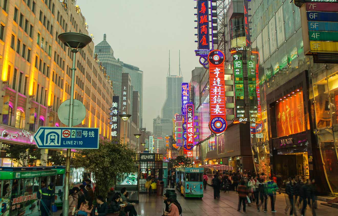 A lively street scene at night in Shanghai with vibrant neon signs and a crowd of people, capturing the city's dynamic atmosphere