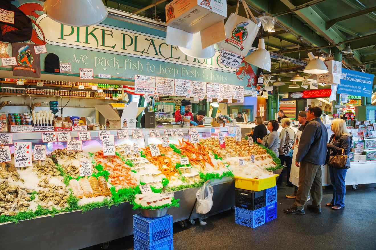 Pike Place Market fish stall in Seattle, bustling with activity and showcasing a variety of fresh seafood on ice, with colorful signage
