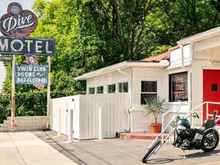 Motel entrance with a vintage sign, white picket fence, and a classic motorcycle parked out front