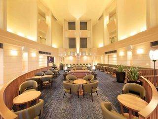 A spacious hotel lobby with multiple seating areas, high ceilings, and elegant lighting, designed for comfort and relaxation.