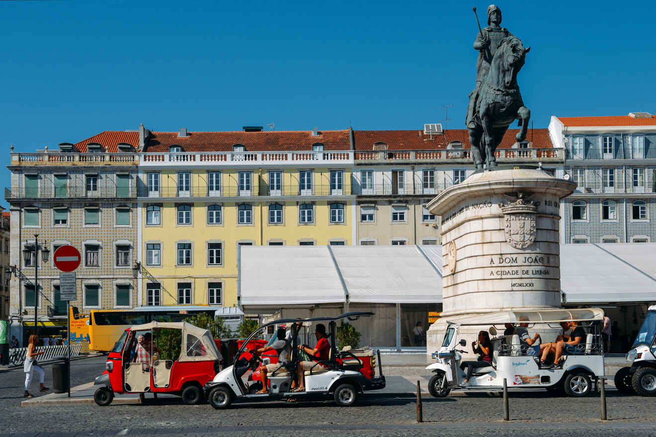 People riding tuk-tuks in front of a statue of a mounted figure in a city square, with a yellow building in the background.