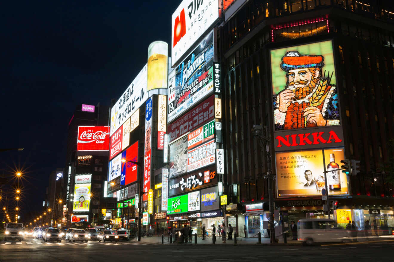 A vibrant night view of a bustling city street lined with brightly lit billboards and neon signs.