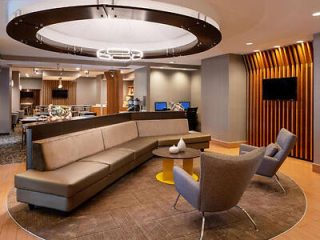 Modern hotel lobby with contemporary furnishings, circular overhead lighting, and a welcoming reception area