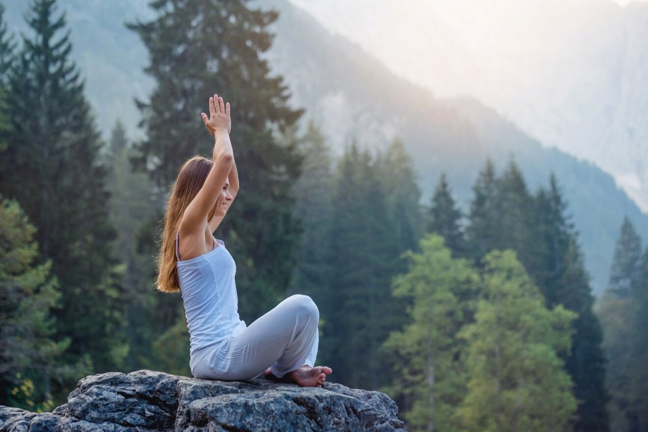 Woman doing yoga on a rock in the mountains