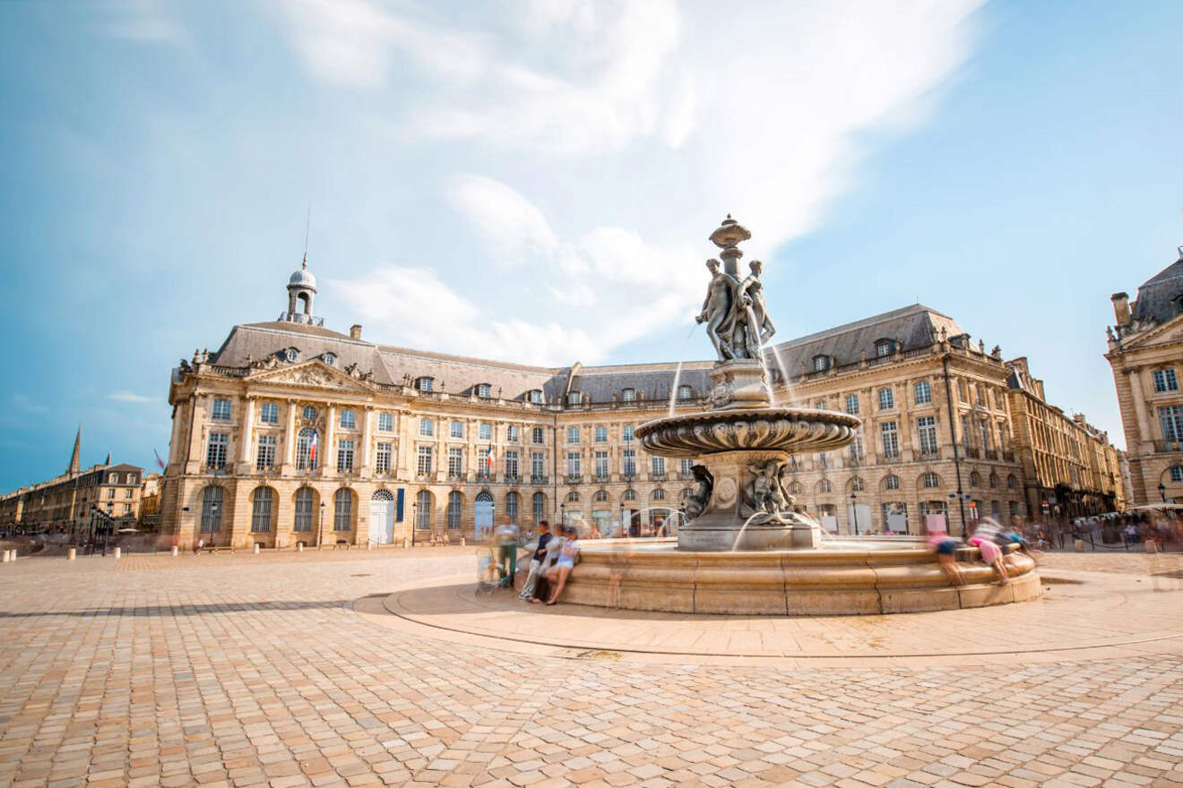 People sitting on a fountain in the middle of a city square in Bordeaux Historic District