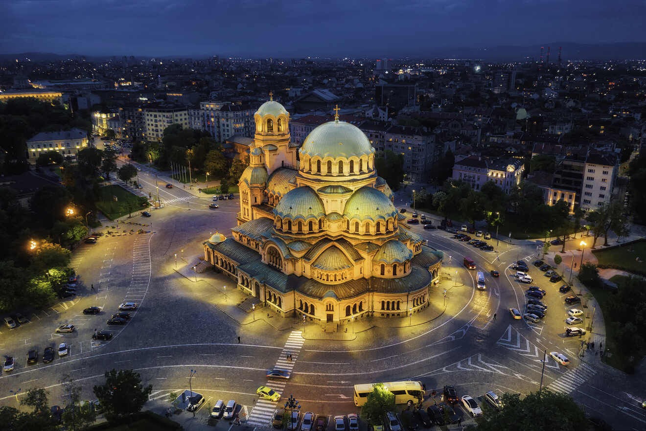 Aerial view of the illuminated Alexander Nevsky Cathedral at night in a cityscape setting.