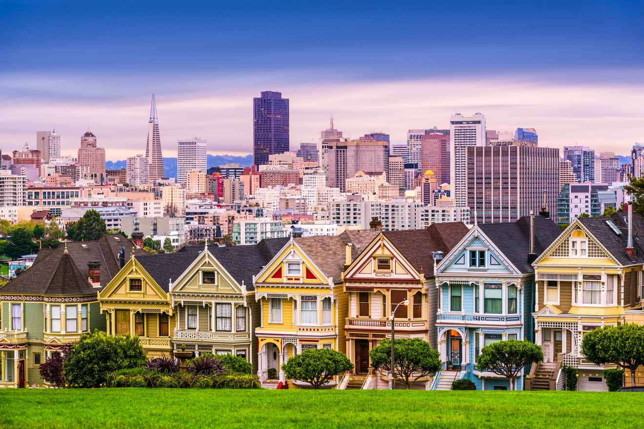 a row of painted houses in front of a city skyline