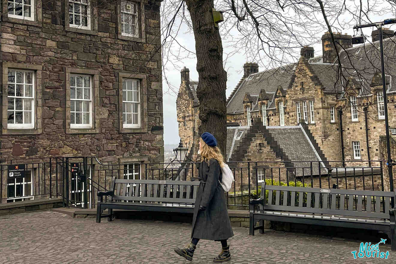 a woman walking down a cobblestone street past a stone building