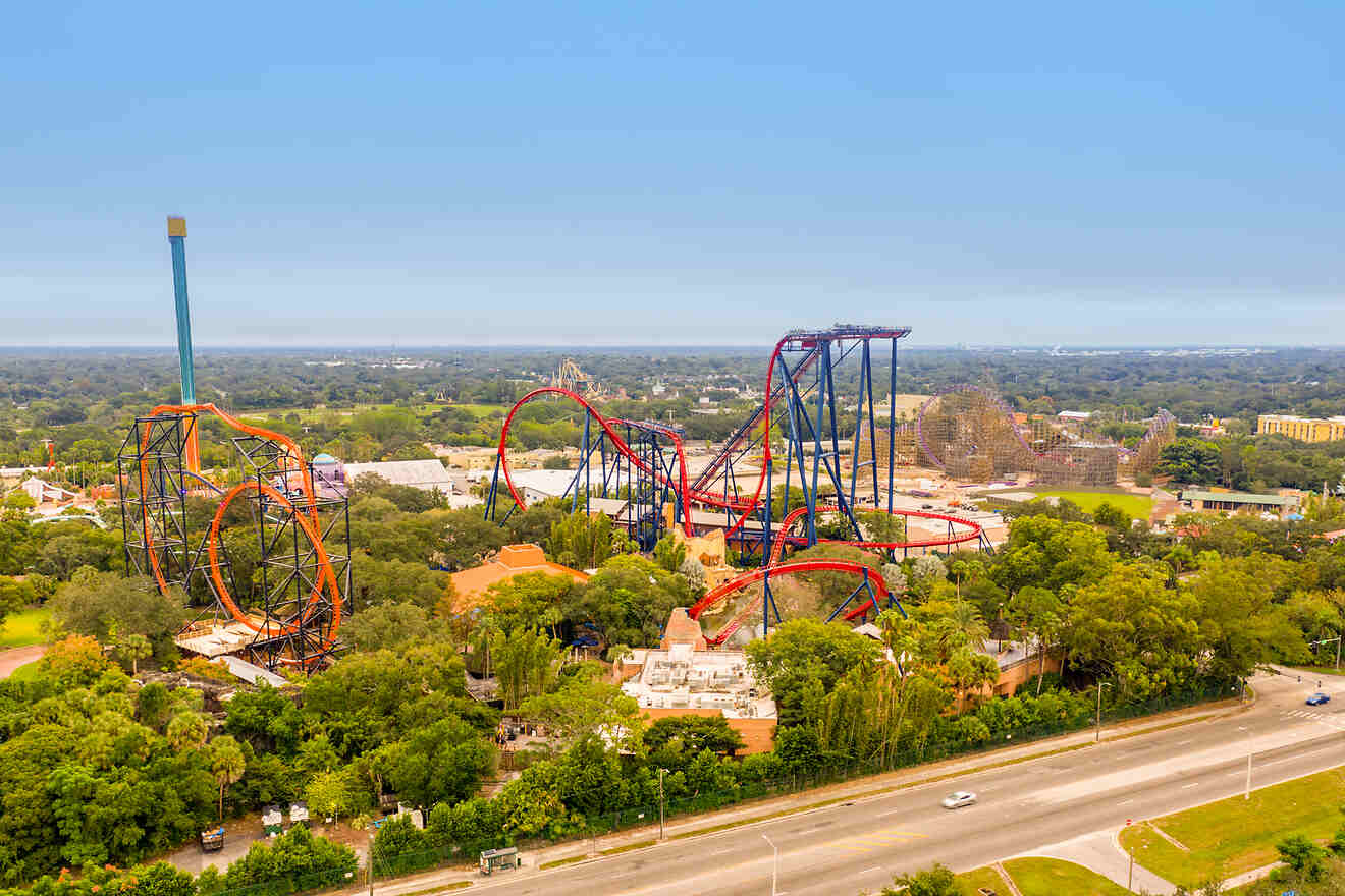 Aerial view of an amusement park with multiple roller coasters and lush greenery surrounding the area