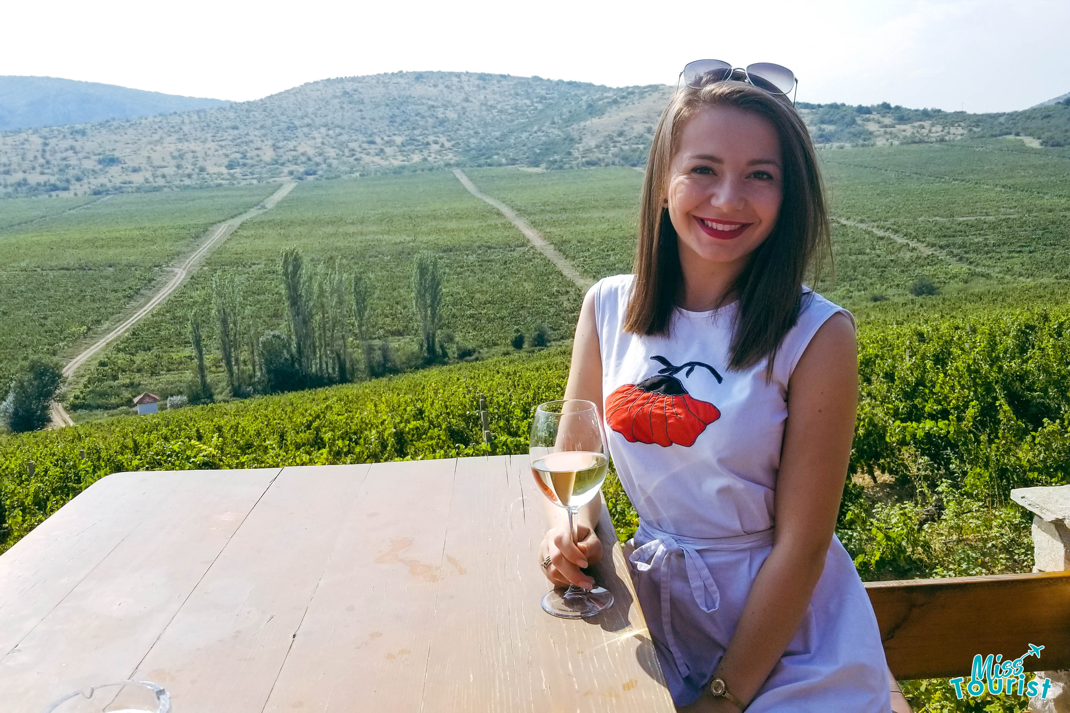 Girl holding a glass of wine with vineyards in the background