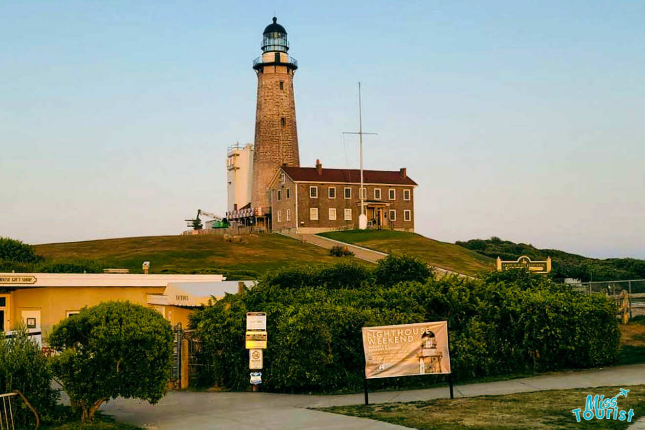 Montauk Point Lighthouse presented at dusk, featuring the renovated building and beacon atop a grassy hill with a 'Lighthouse Weekend' event banner in the foreground, signaling a community event