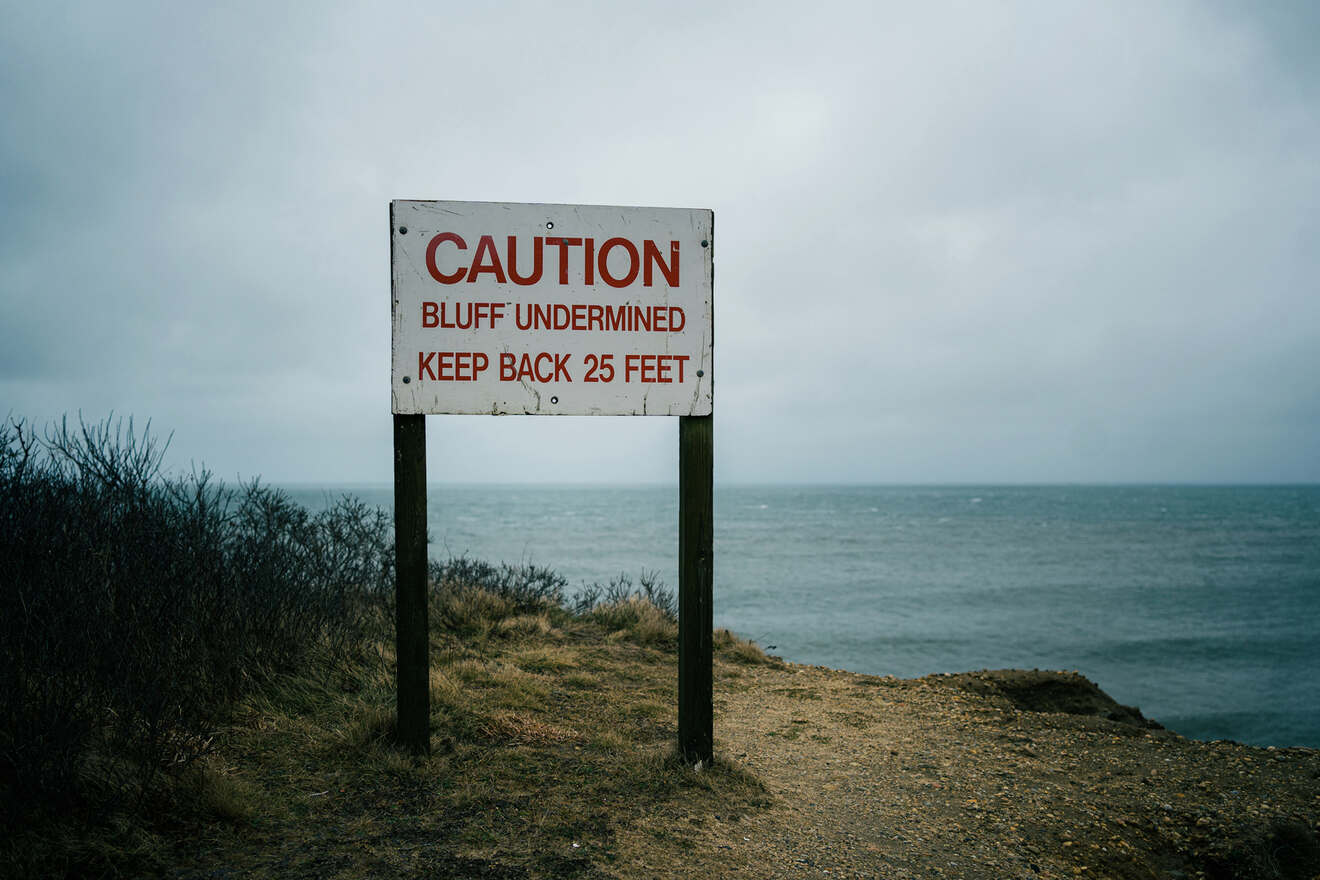 A caution sign on a cliff near the ocean.