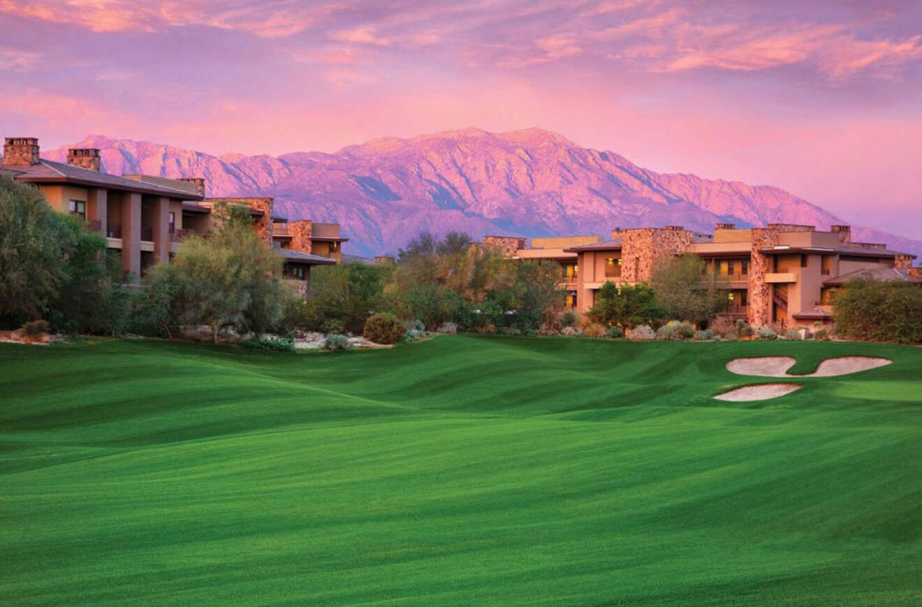 view of a hotel with a golf course at sunset with mountains in the background