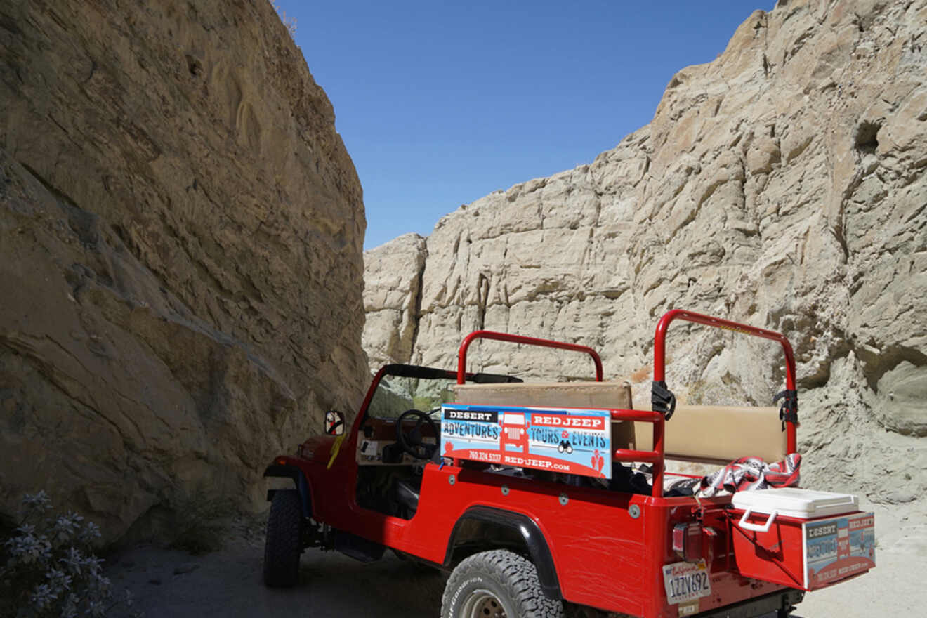red jeep in the desert surrounded by tall rock walls