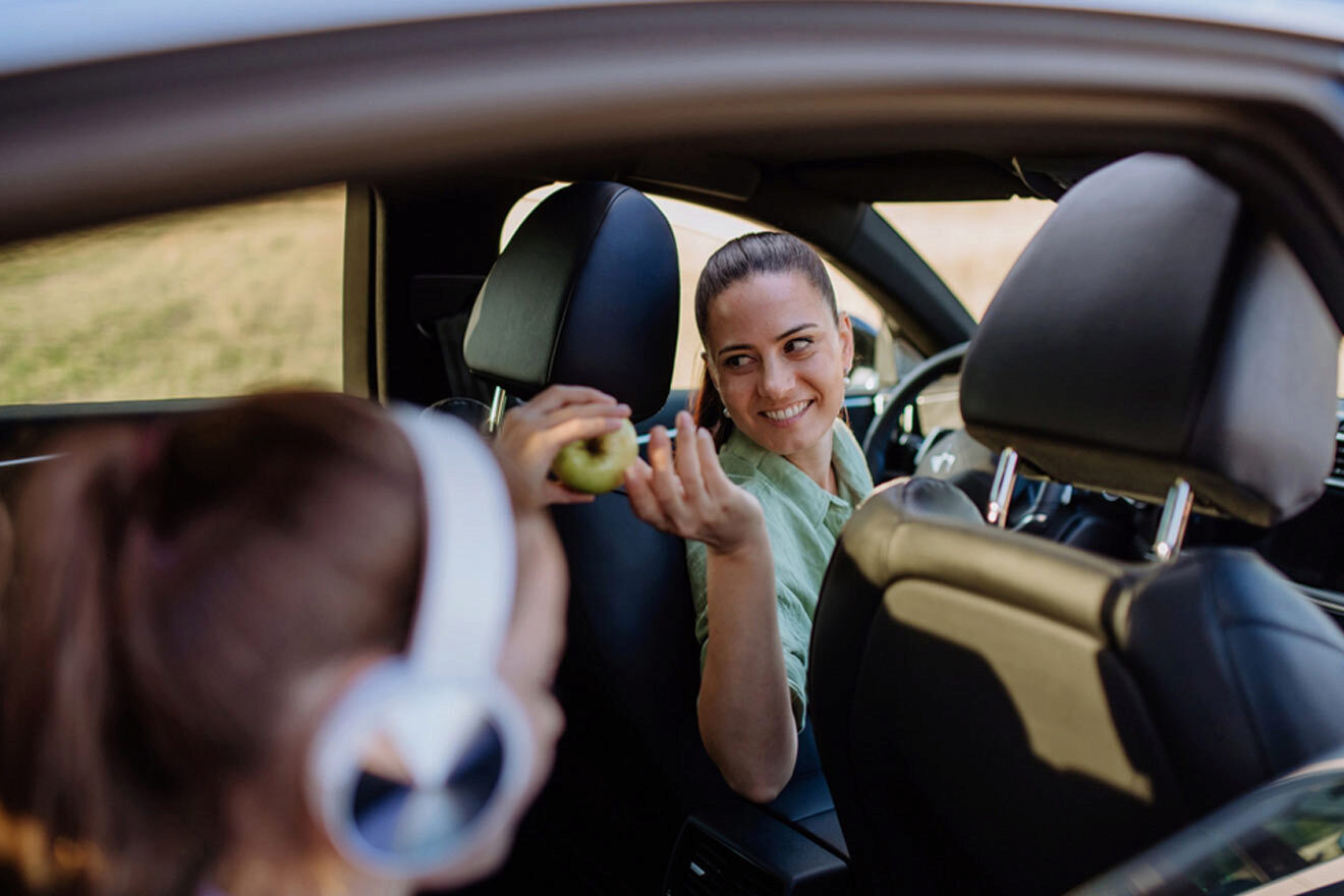 woman offering snacks in the car to the kids