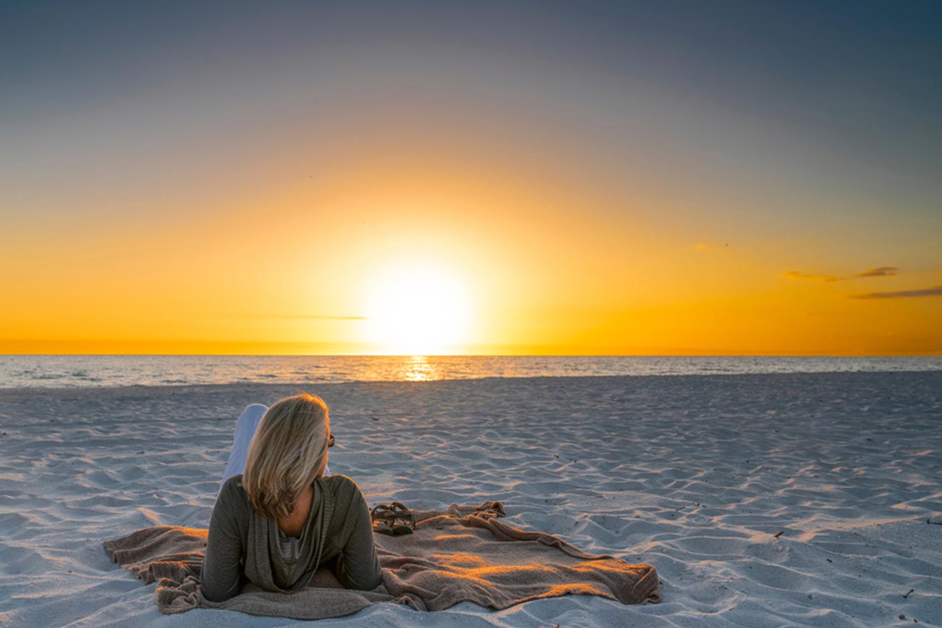 Woman lying on a beach looking out at the sunset