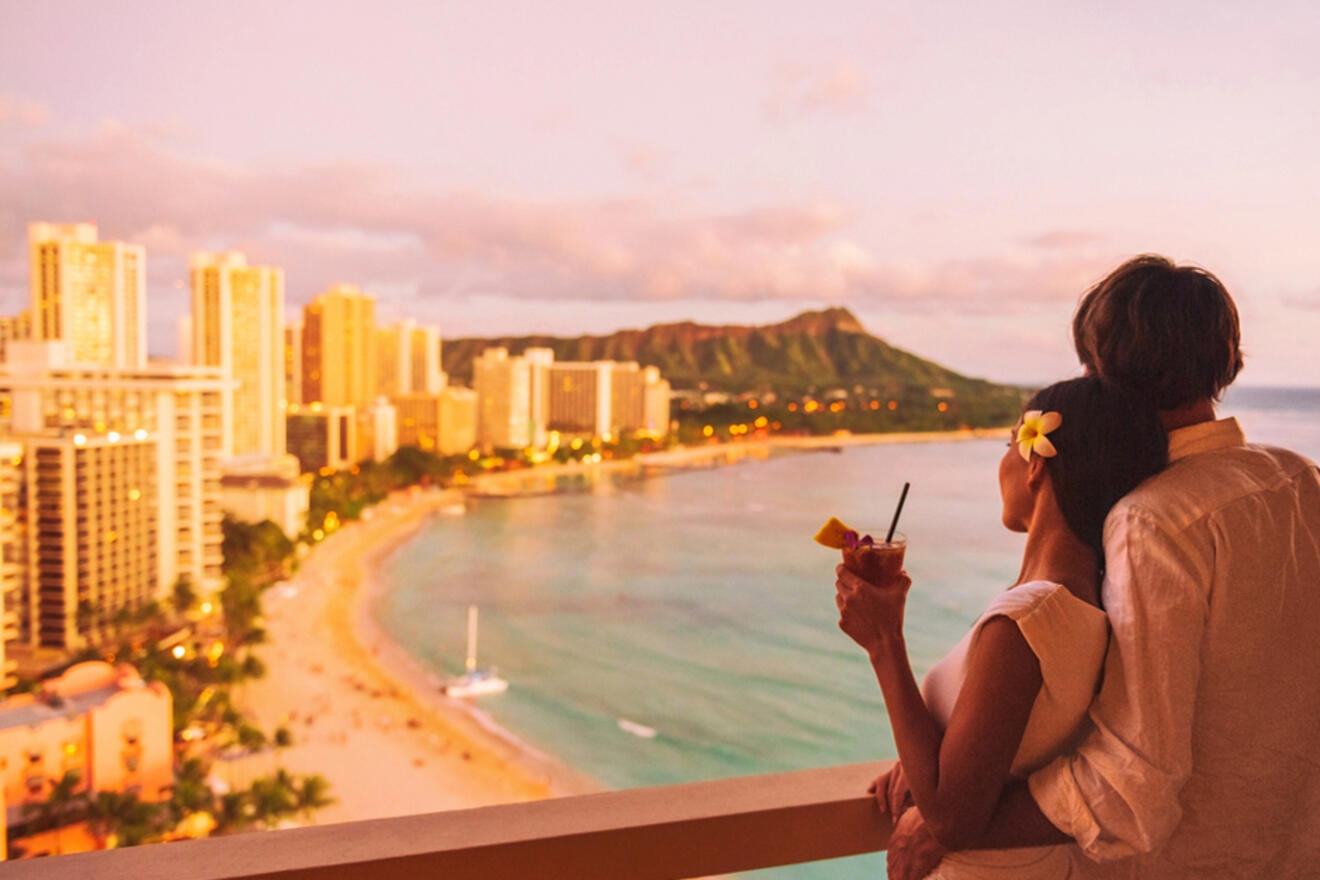 A couple hugging and looking at the Hawaii shoreline from a balcony