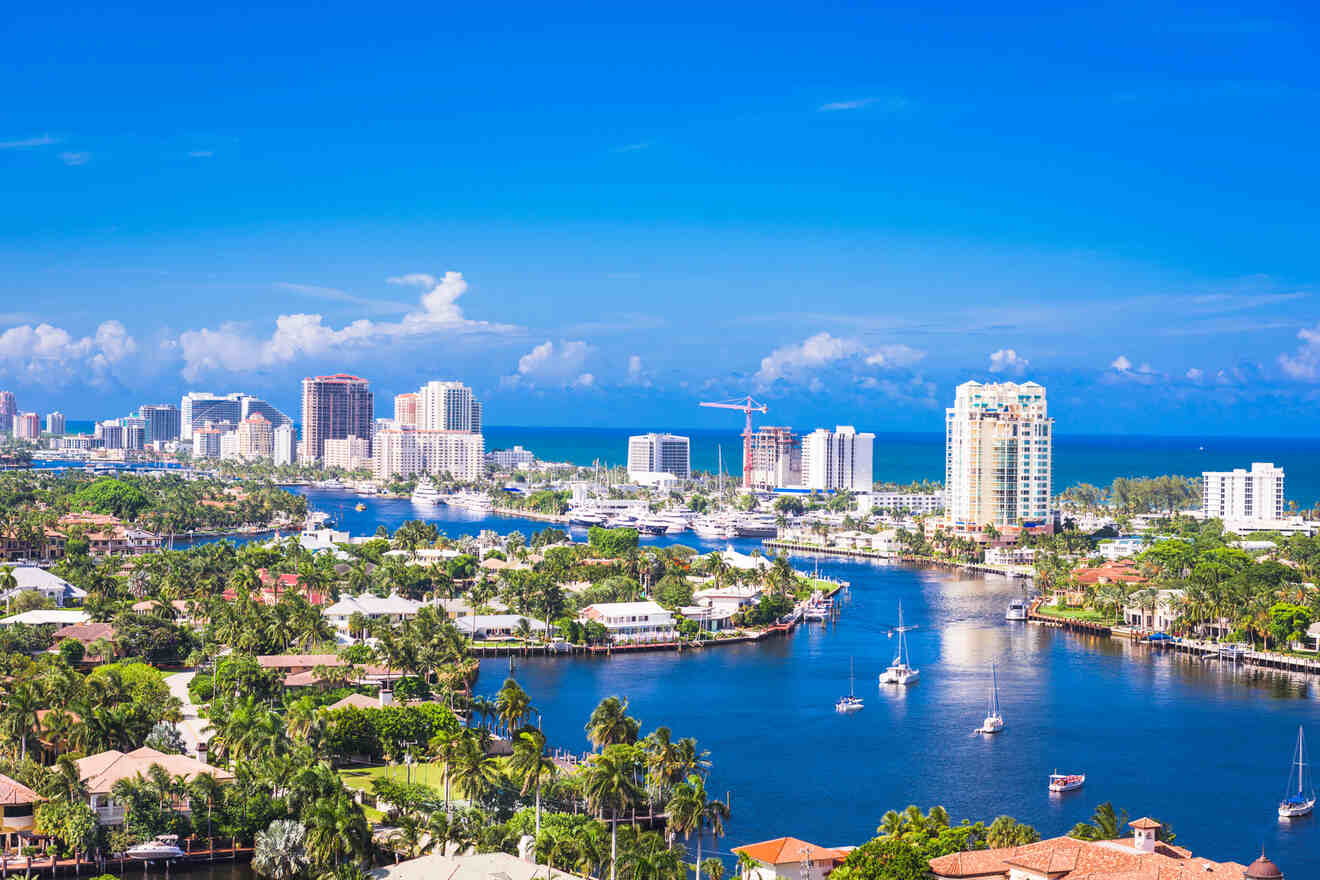 A picturesque aerial view of a Fort Lauderdale city with high-rise buildings along the shore, luxurious yachts dotting the blue waters, and lush greenery enveloping serene residential areas