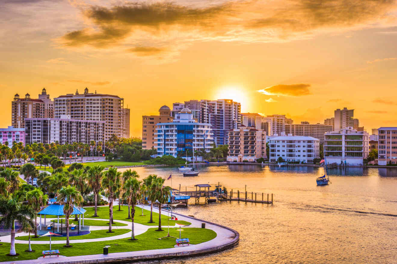 A picturesque waterfront view of Sarasota, Florida, at sunset, with high-rise buildings, palm trees, and boats in the water.