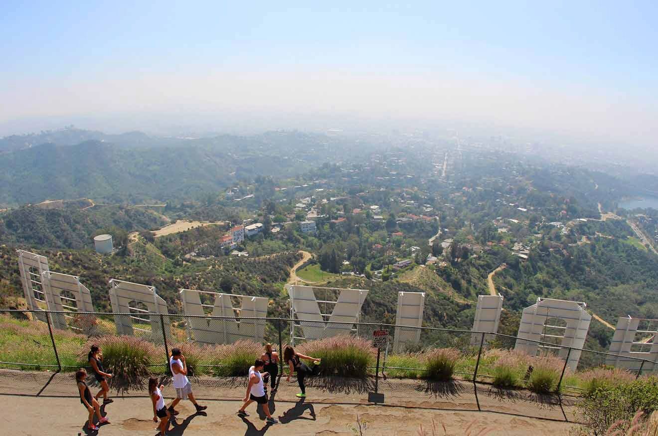 a group of people walking behind the Hollywood sign