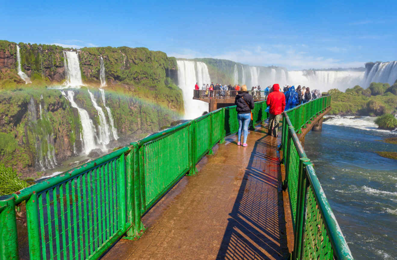 a group of people standing on a bridge near a waterfall