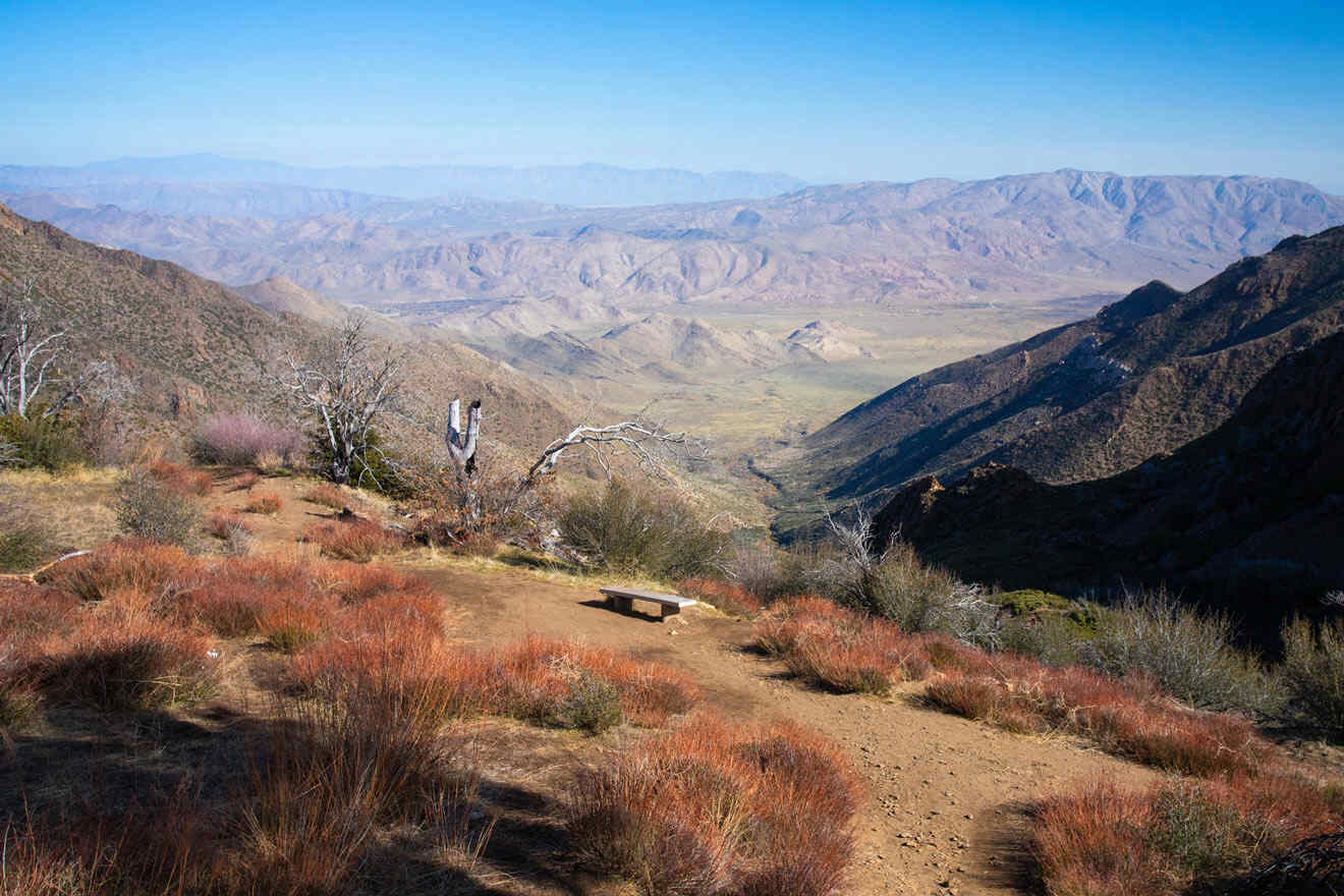 a view of a mountain range with a bench in the foreground