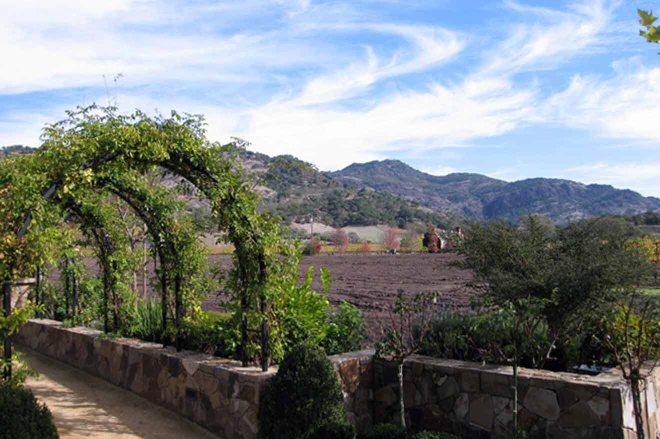 a garden with a stone wall and a stone arch