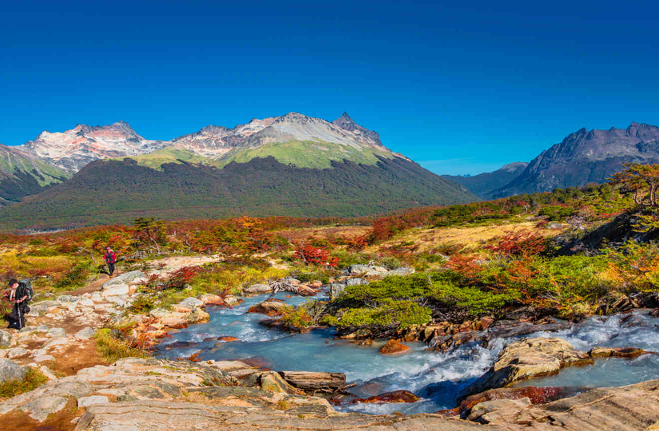 people hiking up a mountain with a river in the foreground