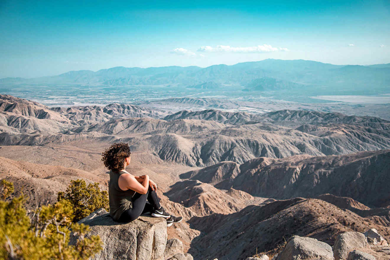 a person sitting on a rock looking out over the mountains