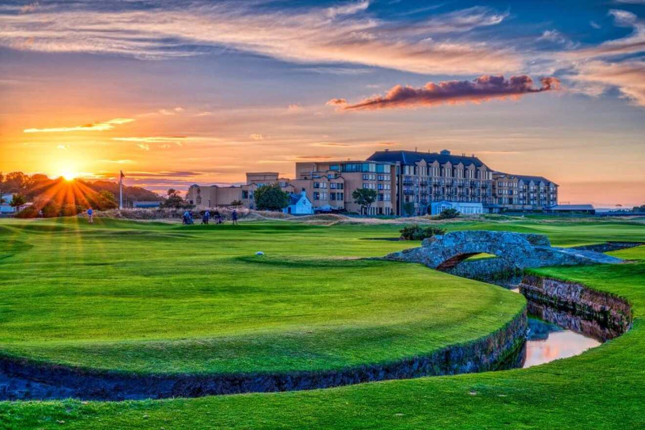 a golf course with a hotel and sunset in the background