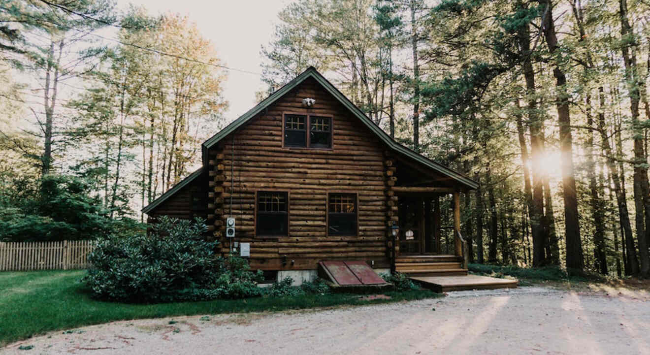 a log cabin sits in the middle of a wooded area at sunset