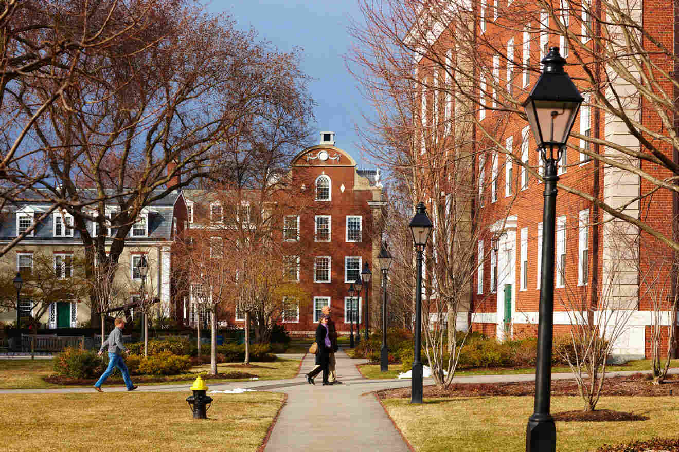 Harvard college campus in Boston with students walking along the pathways between traditional red-brick buildings and bare trees