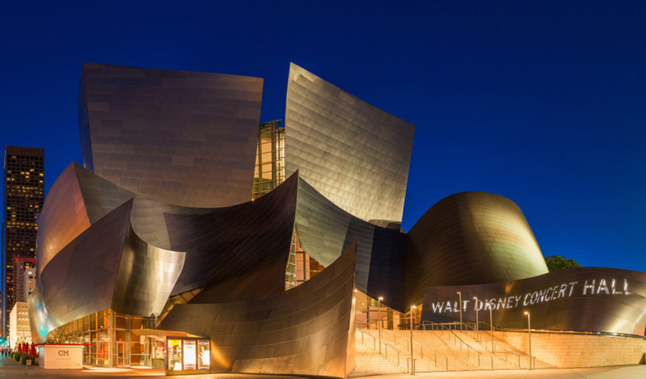The Walt Disney Concert Hall in Los Angeles gleams under night lights, showcasing its modern, metallic architecture and dynamic angles.
