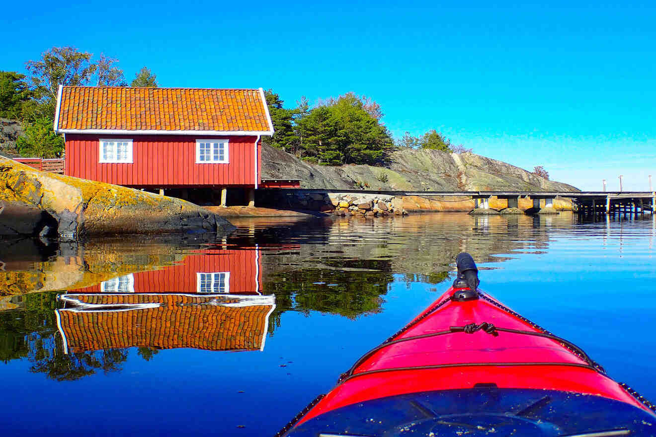 red kayak in the water with a red house in the background