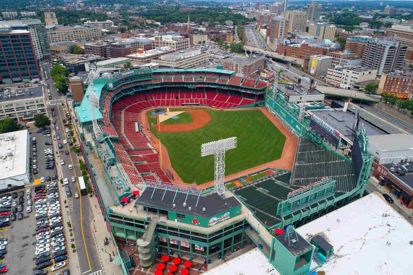 Aerial view of Fenway Park in Boston, showcasing the iconic baseball stadium's green field, red seating, and the surrounding cityscape on a bright day