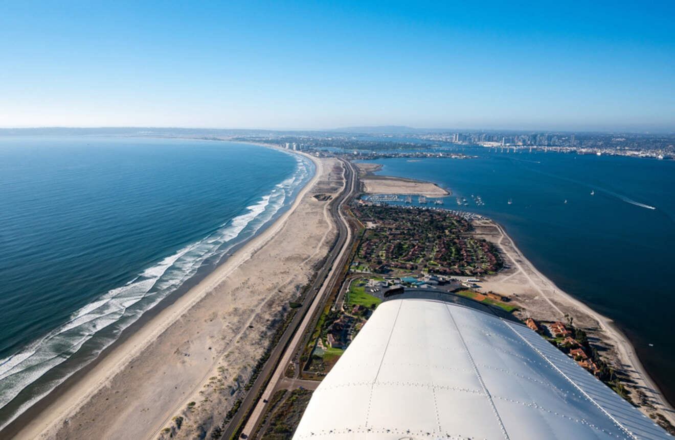 an airplane wing flying over a beach and ocean