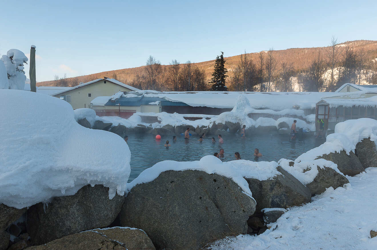 a group of people in a hot springs surrounded by snow