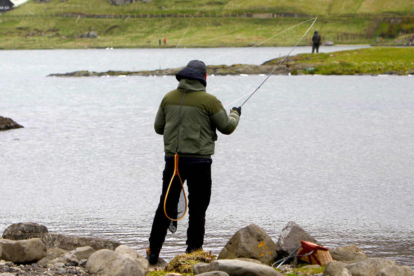 a man standing on a rocky shore holding a fishing rod