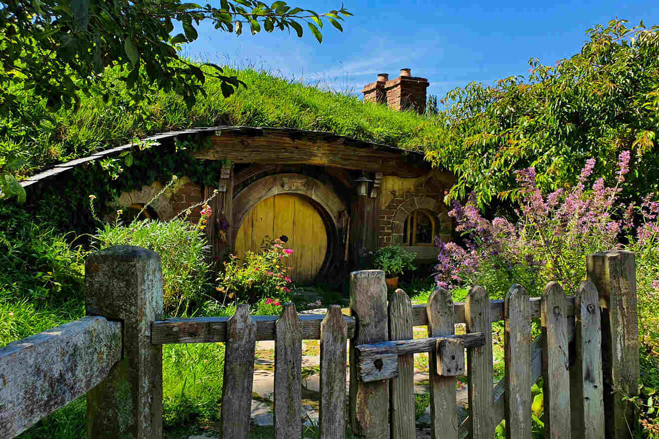 a hobbit house with a green roof and a wooden fence