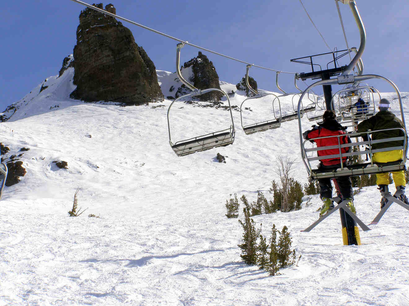 People riding on a ski lift in snowy mountains
