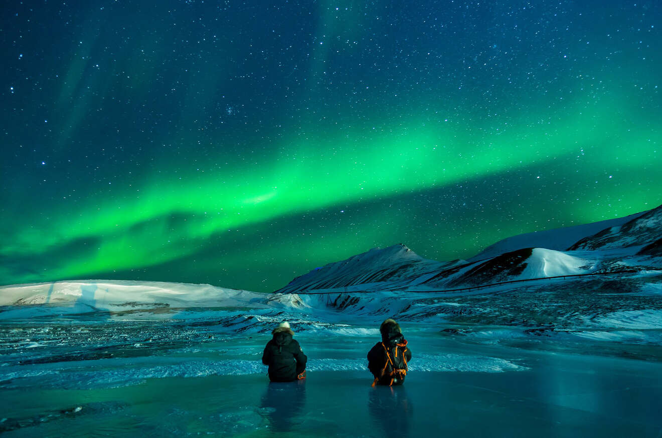 Two people sitting and looking at Aurora Borealis