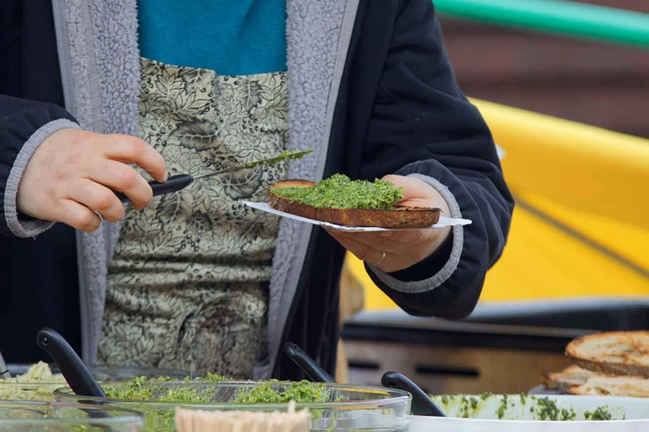 person holding bread with pesto on it