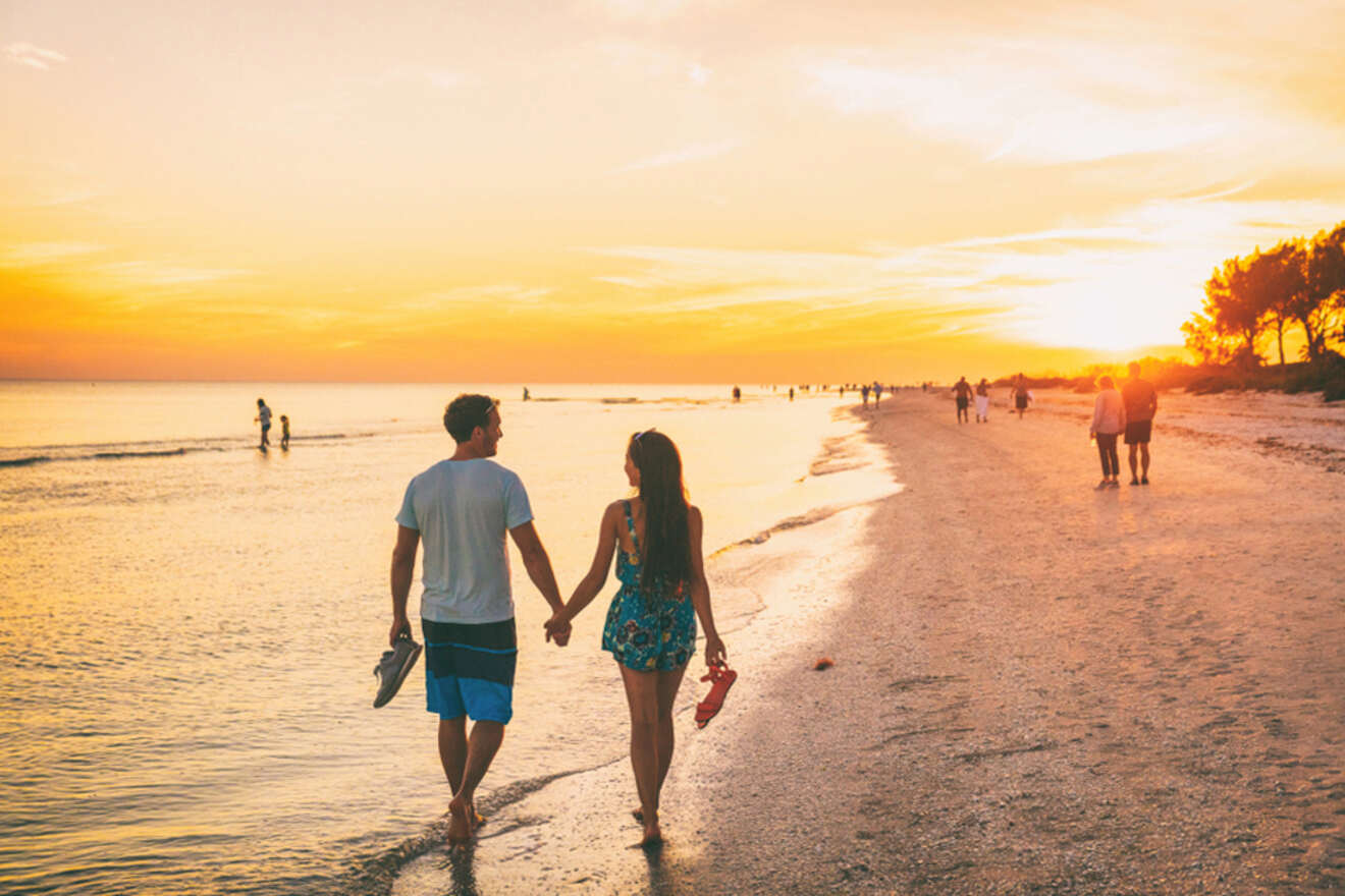 couple taking a walk on the beach while watching the sunset