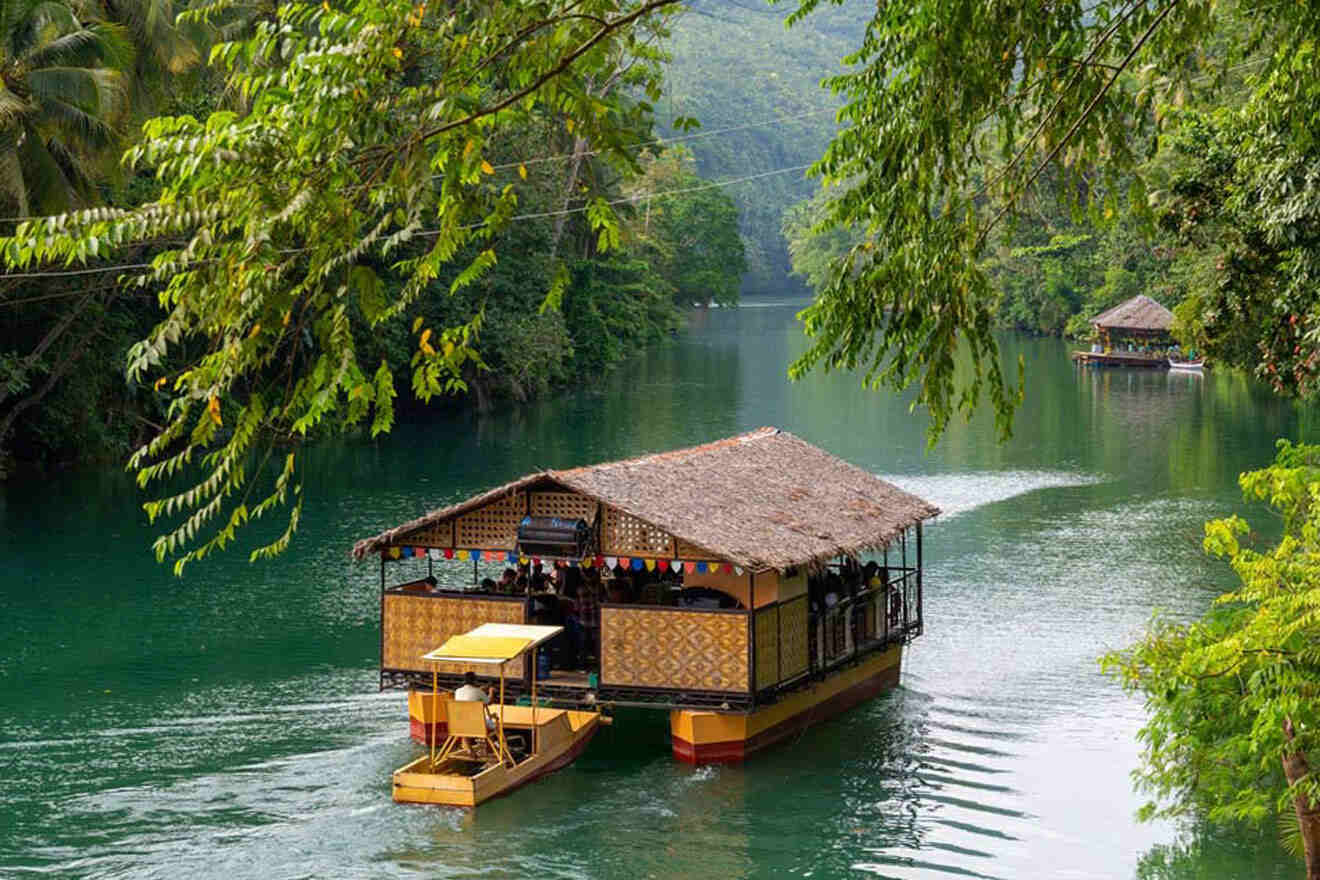 a house boat floating down a river next to a forest