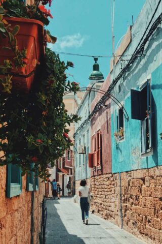 a woman walking down a street next to buildings