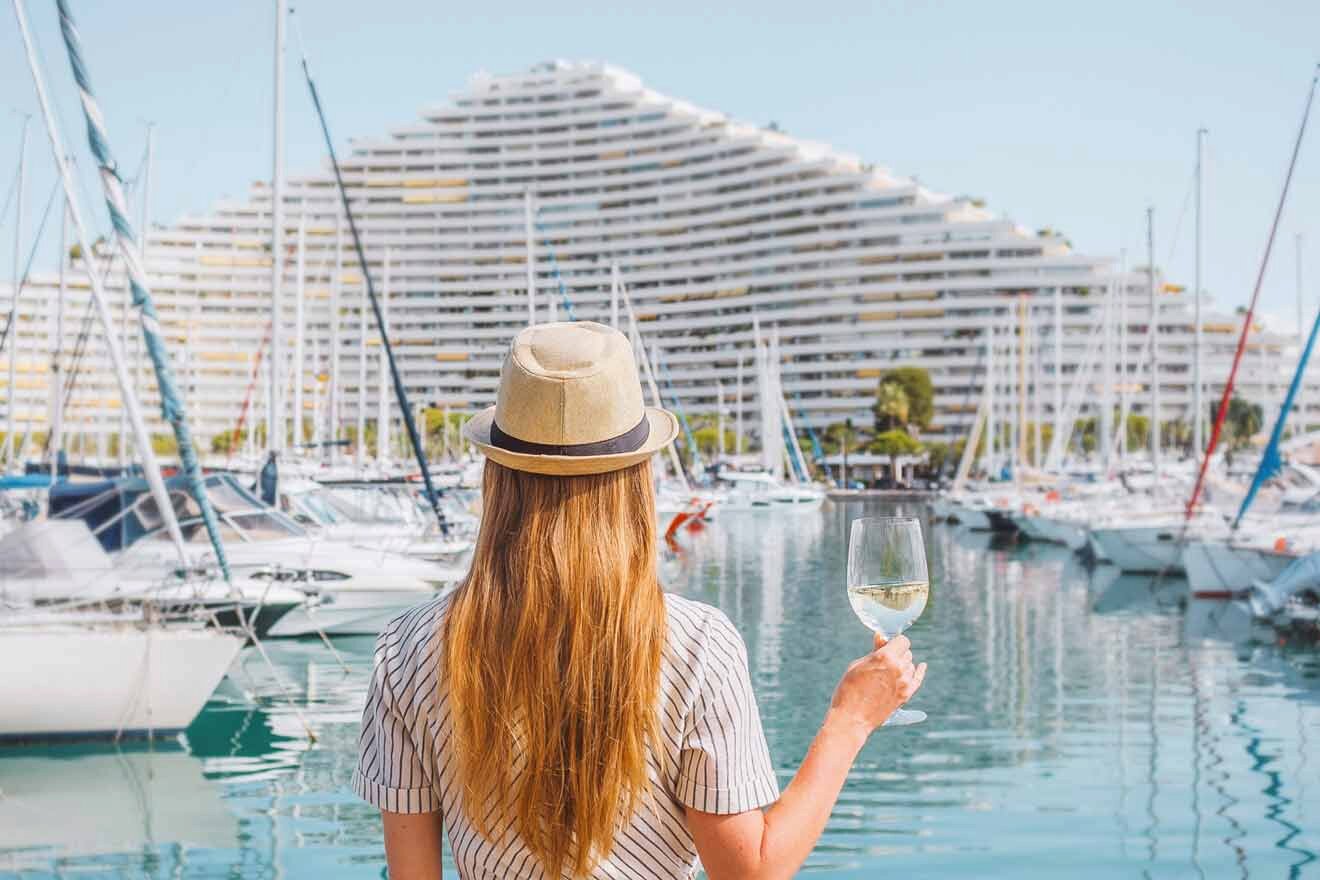 woman holding a glass of wine in her hand and watching boats in the harbour