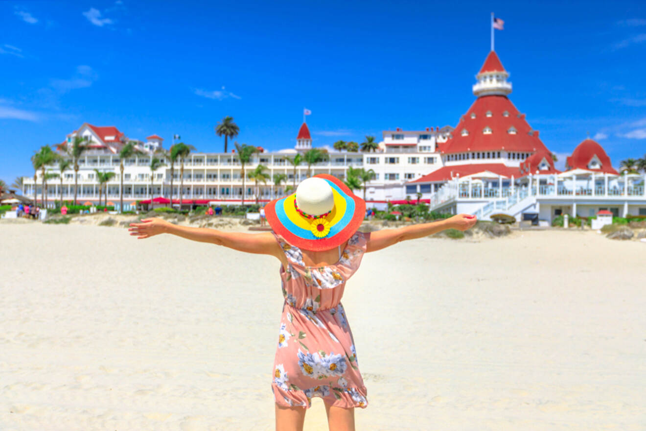 A girl in a sunhat with a flower spreading her hands in front of a hotel