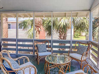 chairs and table on a terrace with palm trees